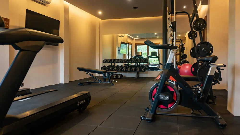 A gym room with several pieces of exercise equipment.