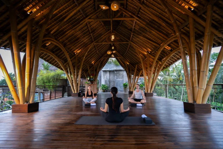 An instructor leading a yoga session with two tourists.